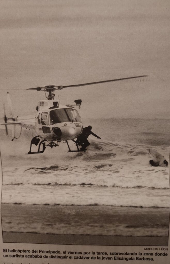 Imagen de un rescate de una víctima por parte de un surfista. Un helicóptero de salvamento se aproxima con un bombero dispuesto a saltar. El viento de las hélices está haciendo volar la tabla de surf. 