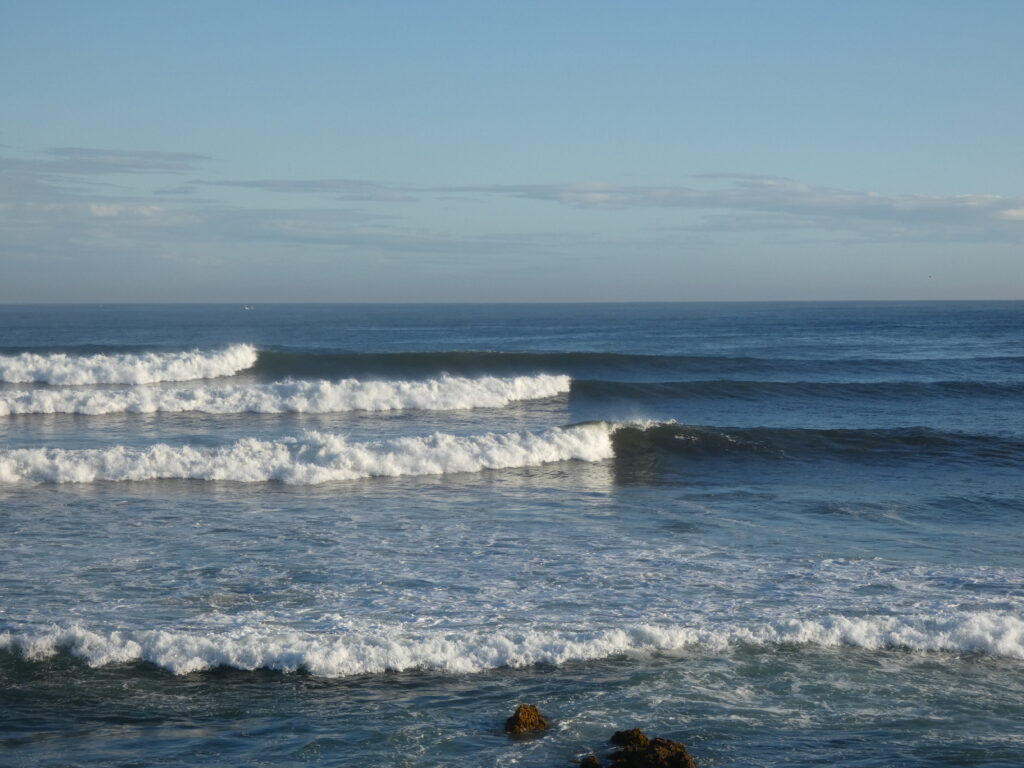 Una serie de olas solitarias rompe en una playa de fondo de roca sin que nadie haga surf en ellas.